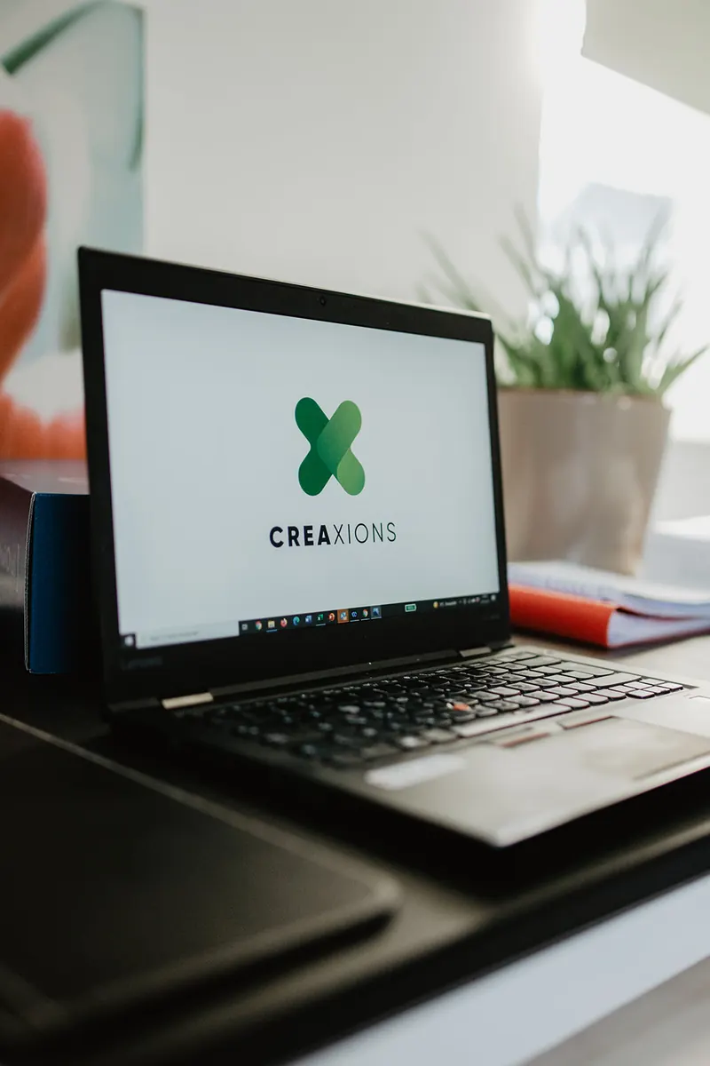 Ordinateur affichant le logo Créaxions